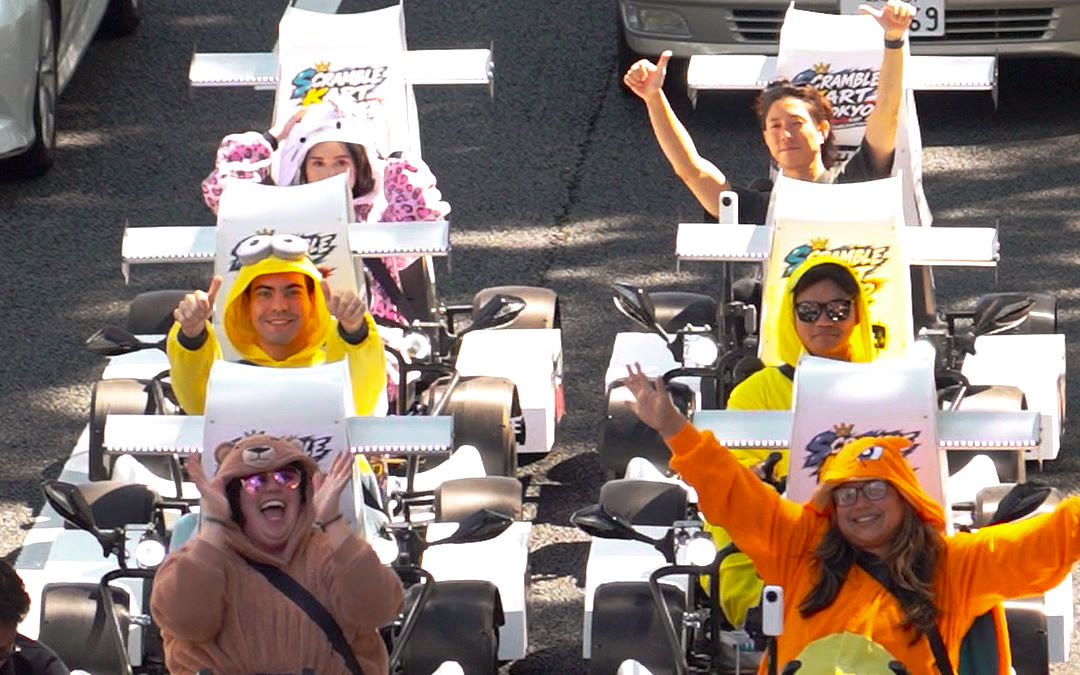 A guest in a character onesie driving a SCRAMBLE KART TOKYO go-kart on a Tokyo street